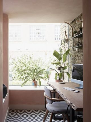 The study featuring an exposed brick wall and large natural wood table, with patterned tiles on the floor