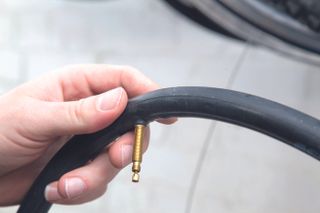 fix a puncture mend an inner tube image here shows a hand holding up a inner tube with a presta valve on display