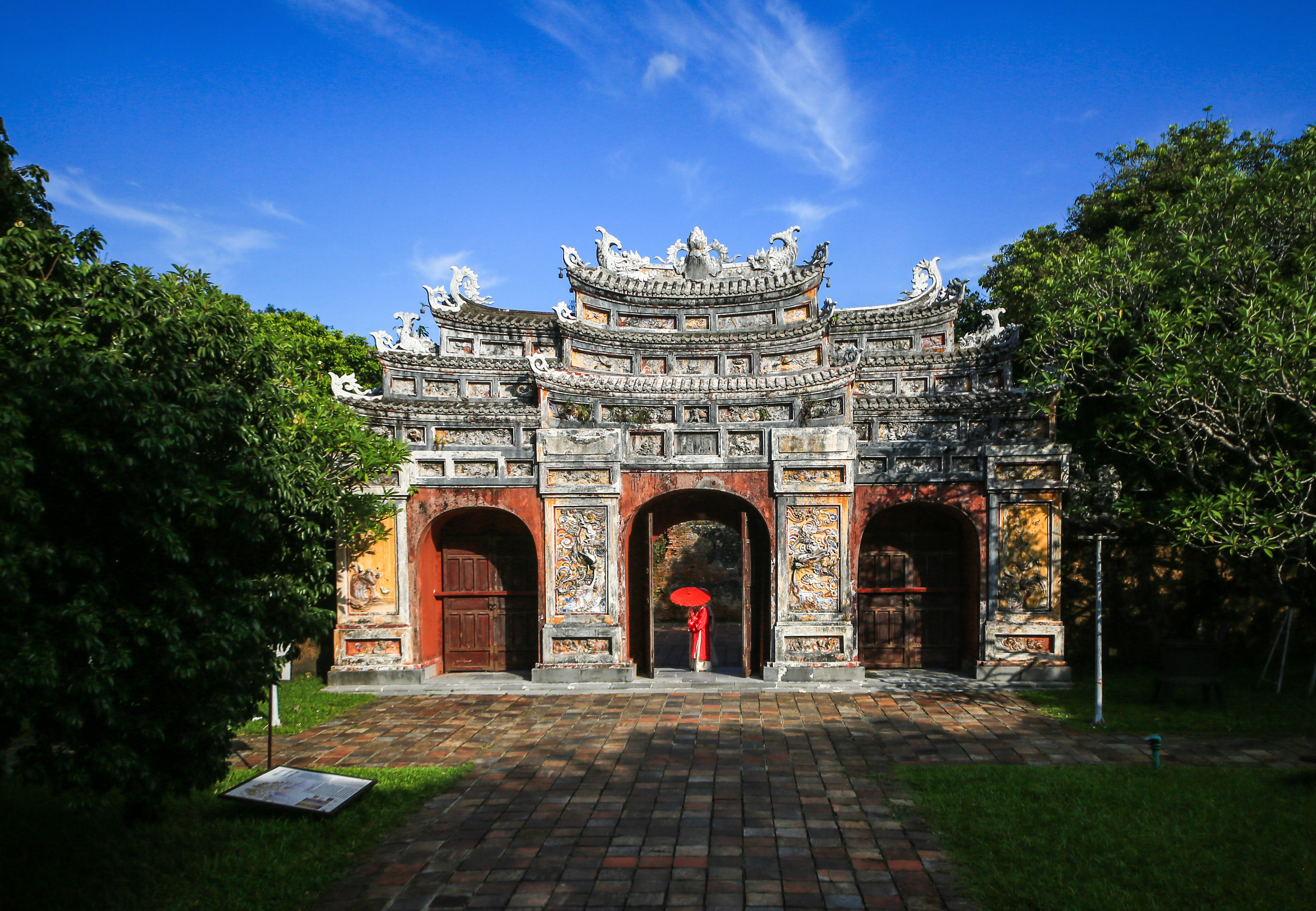 A person wearing red stands in an archway in the Hue citadel
