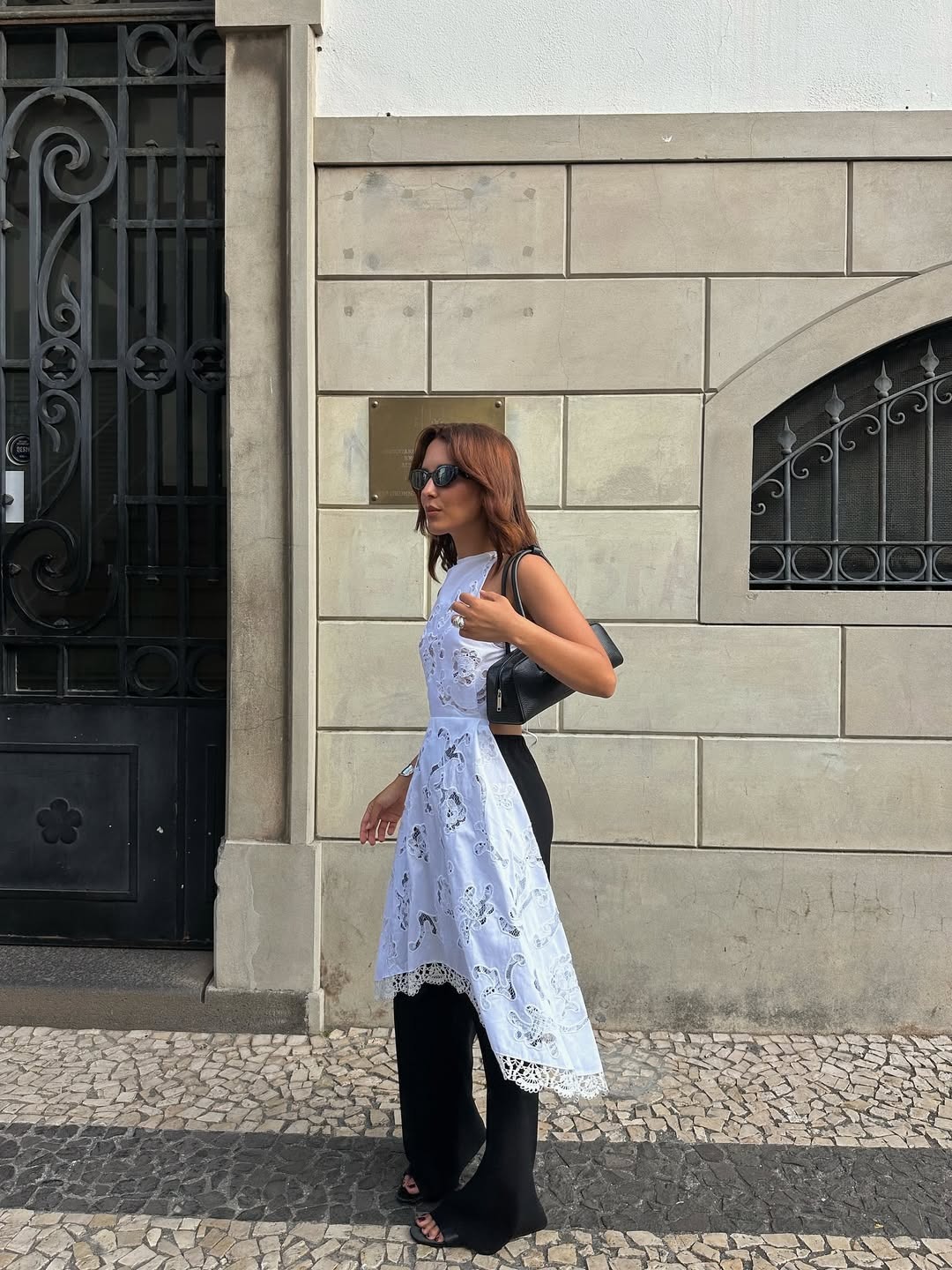 @deborabrosa wearing a white eyelet dress with black trousers.