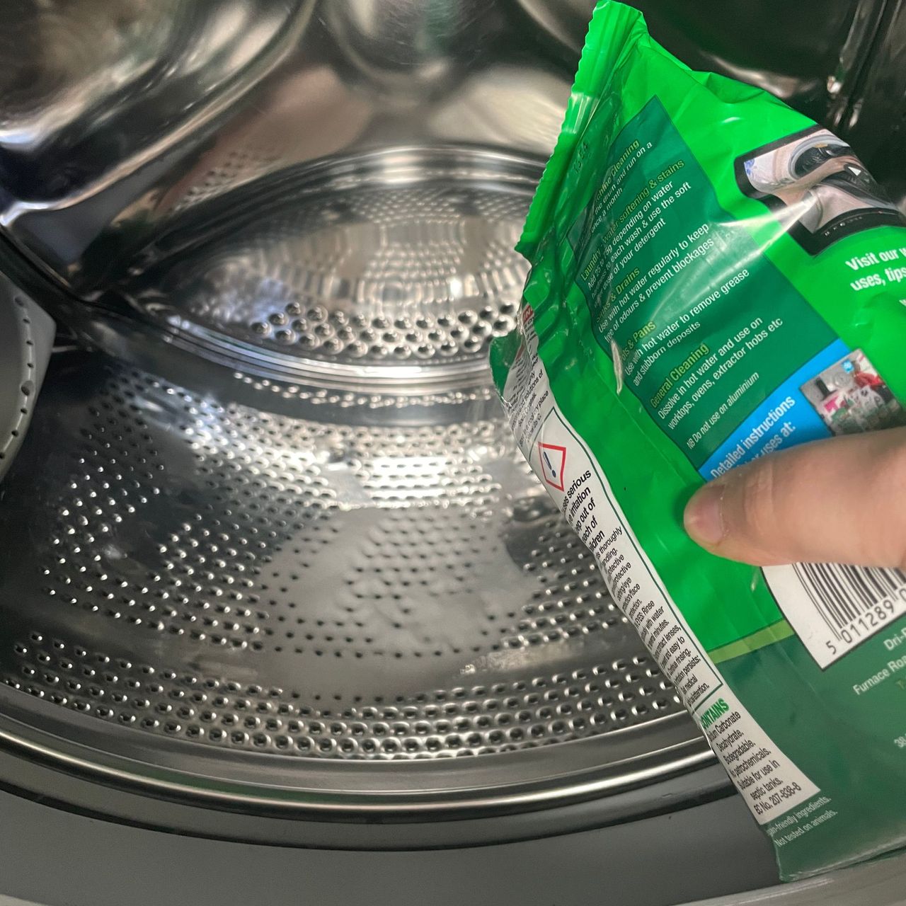 Pouring soda crystals into a washing machine drum
