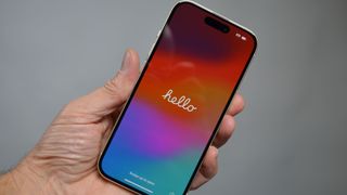 iPhone 15 i hånden med ordet «hello» på skærmen.