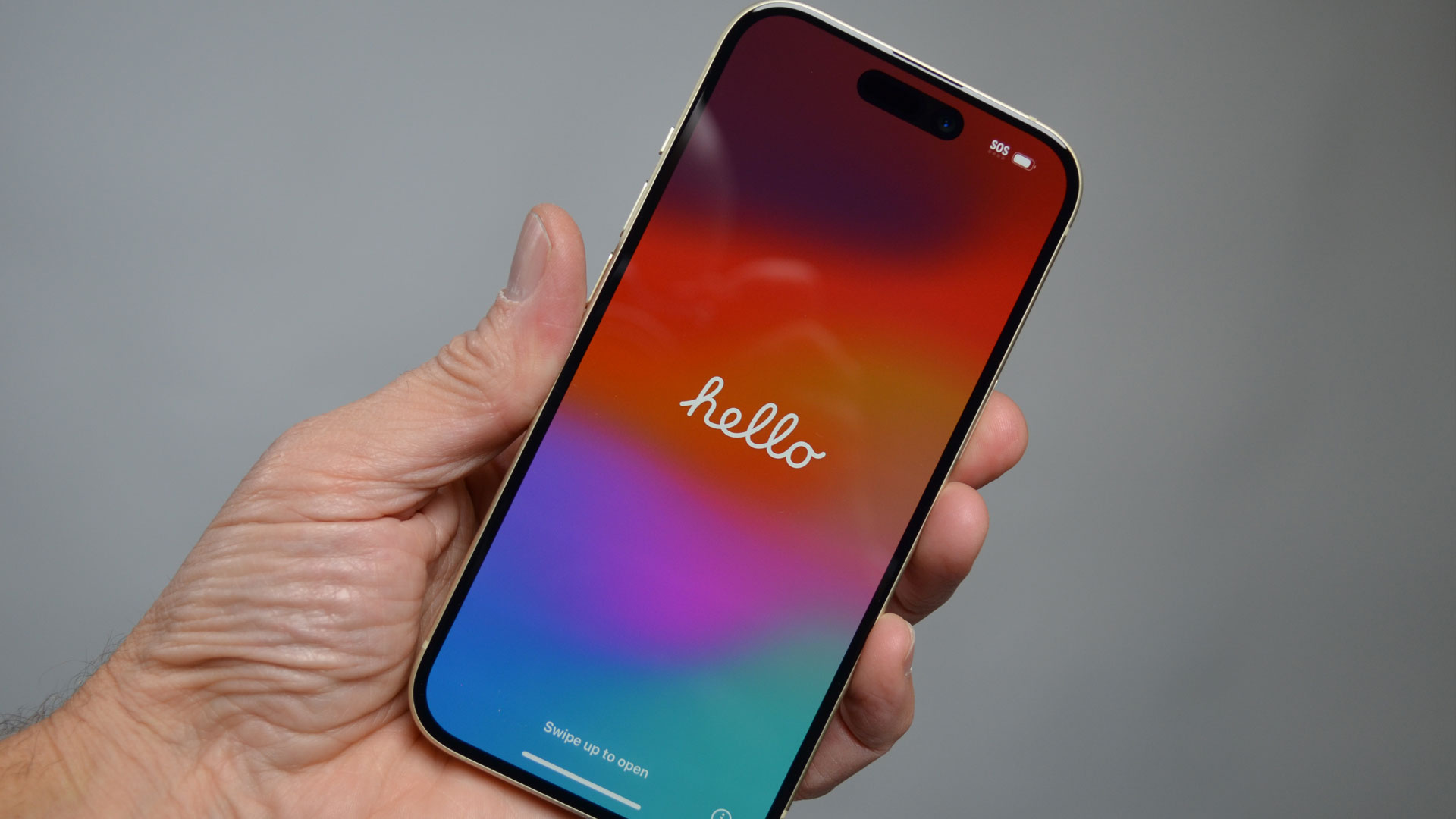 iPhone 15 i en hånd med ordet «hello» på skjermen.