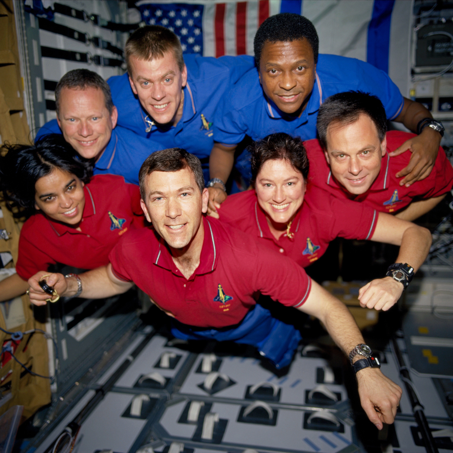 During the STS-107 mission, the crew appears to fly toward the camera in a group photo aboard the Space Shuttle Columbia. On the bottom row (L to R) are astronauts Kalpana Chawla, mission specialist; Rick D. Husband, mission commander; Laurel B. Clark, mi