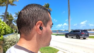 Listing image for best wireless earbuds under $100 showing active noise cancellation being tested on the 1More PistonBuds Pro