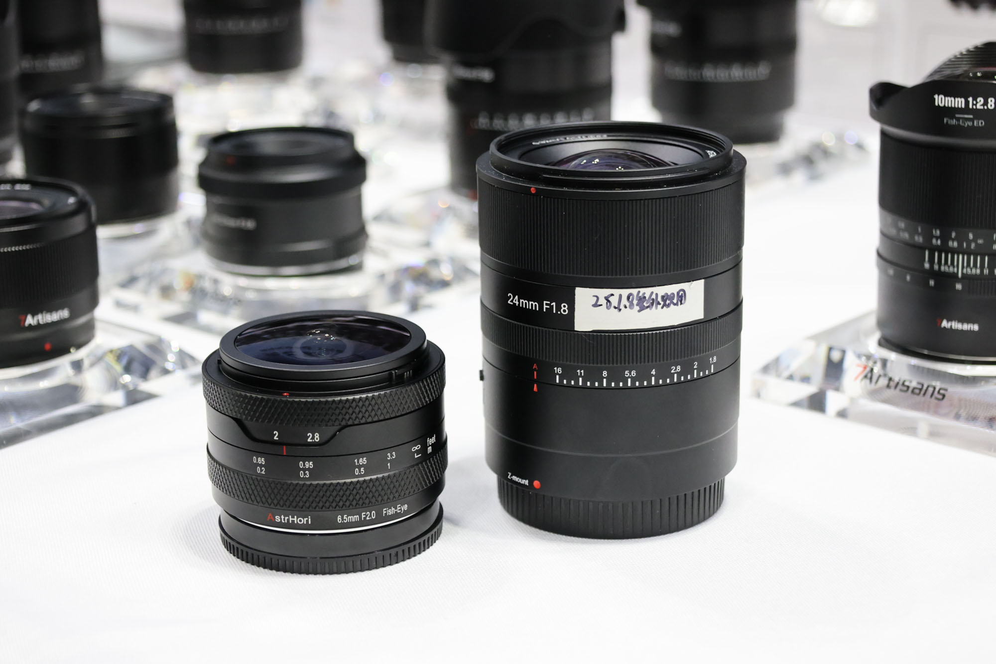 Array of 7Artisans lenses on a white display table at CP+ 2025 photography show.