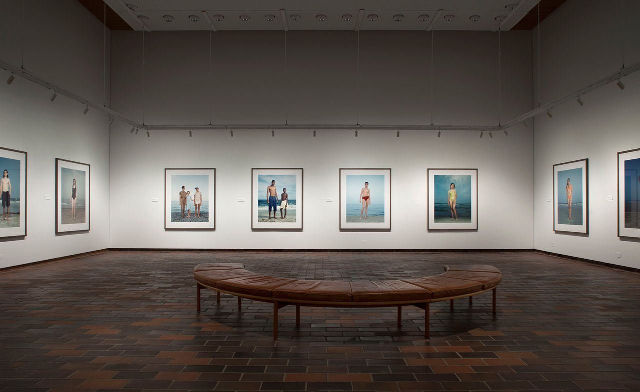 Framed photos of people in swimwear on walls and curved bench in middle of room