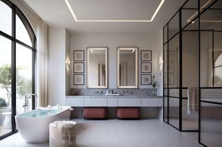 White bathroom with white tub, twin sink & mirrors, and large windows.