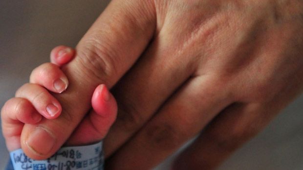 A newborn baby holds onto his mother&amp;#039;s finger 