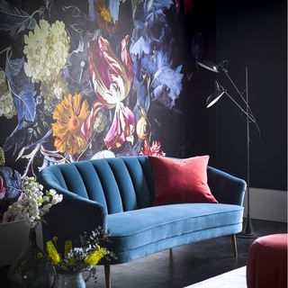 Floral wallpaper living room with a blue sofa and red pillow with floral décor and a modern lamp