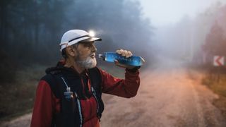 Runner drinking water from bottle on trail