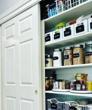 An image of kitchen pantry with a cream door and white shelves inside, showing items that are neat and ordered