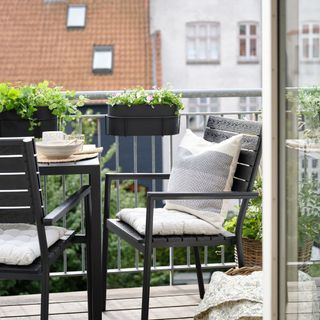 A bistro set with grey outdoor cushions on a balcony