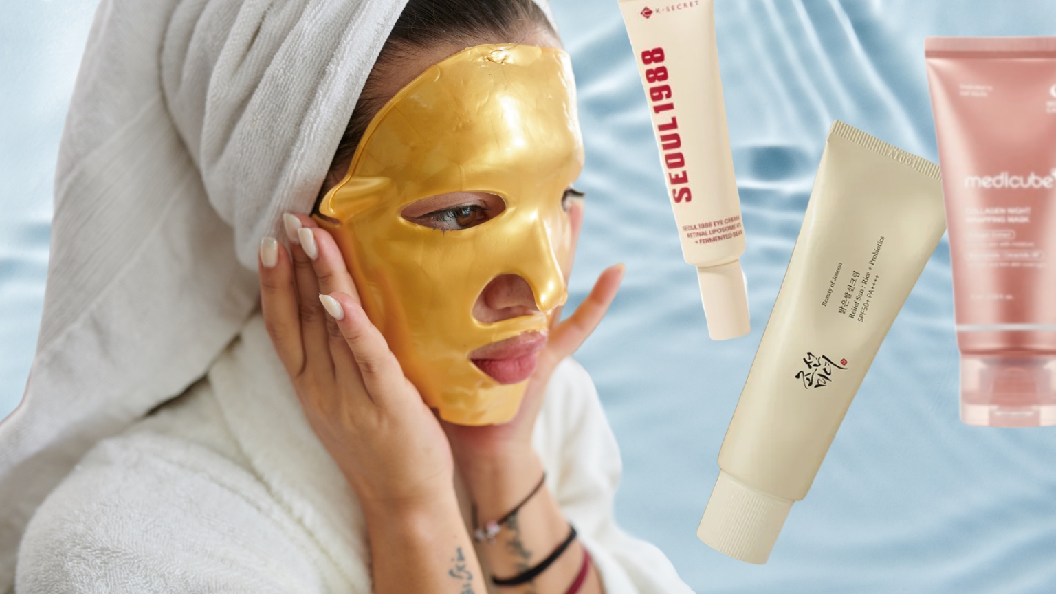 woman in a gold sheet mask and robe with three bottles of skincare