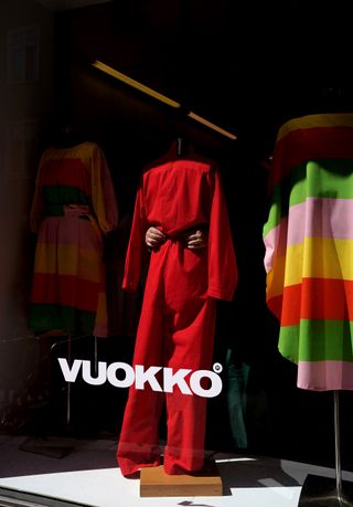 Vuokko shop front in helsinki, red jumpsuit and two striped dresses on mannequins