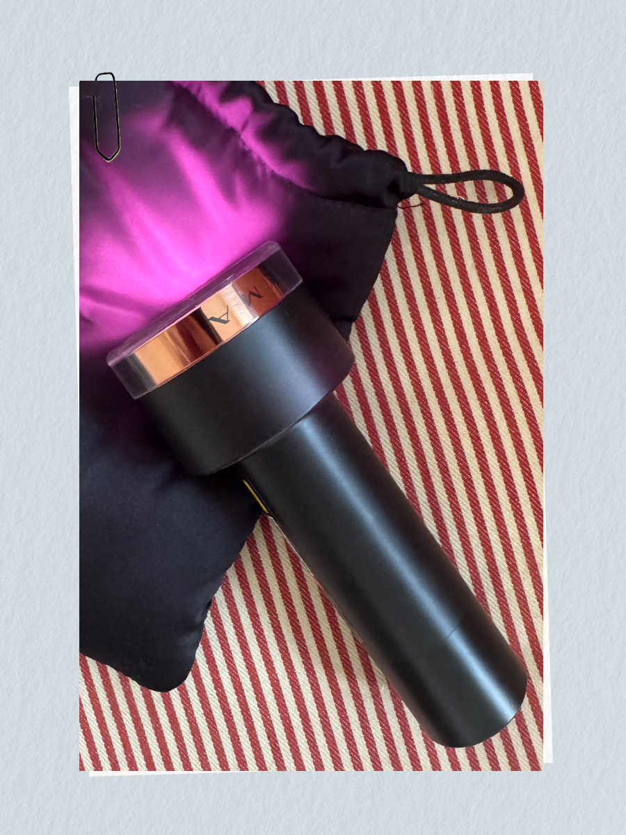 A photo of the Lyma Laser Pro device with glowing light, sitting on a red striped surface and the Lyma storage bag
