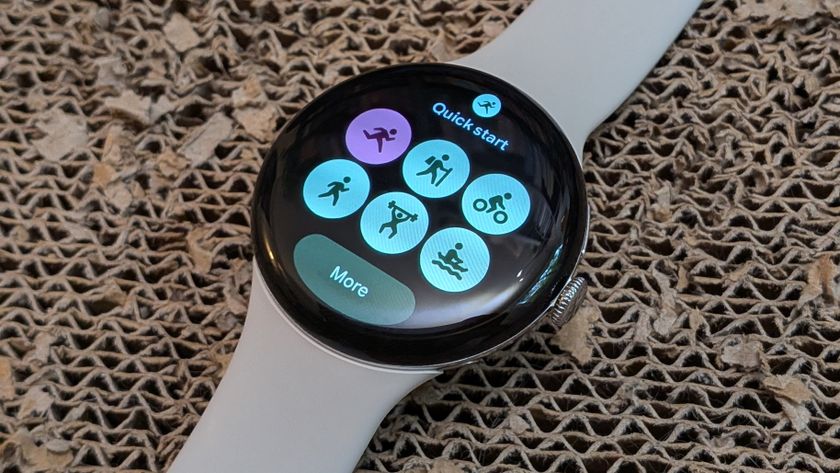 A Pixel Watch 4 sitting on a scratch pad showing the Fitbit Quick Start Tile with blue theming for the buttons