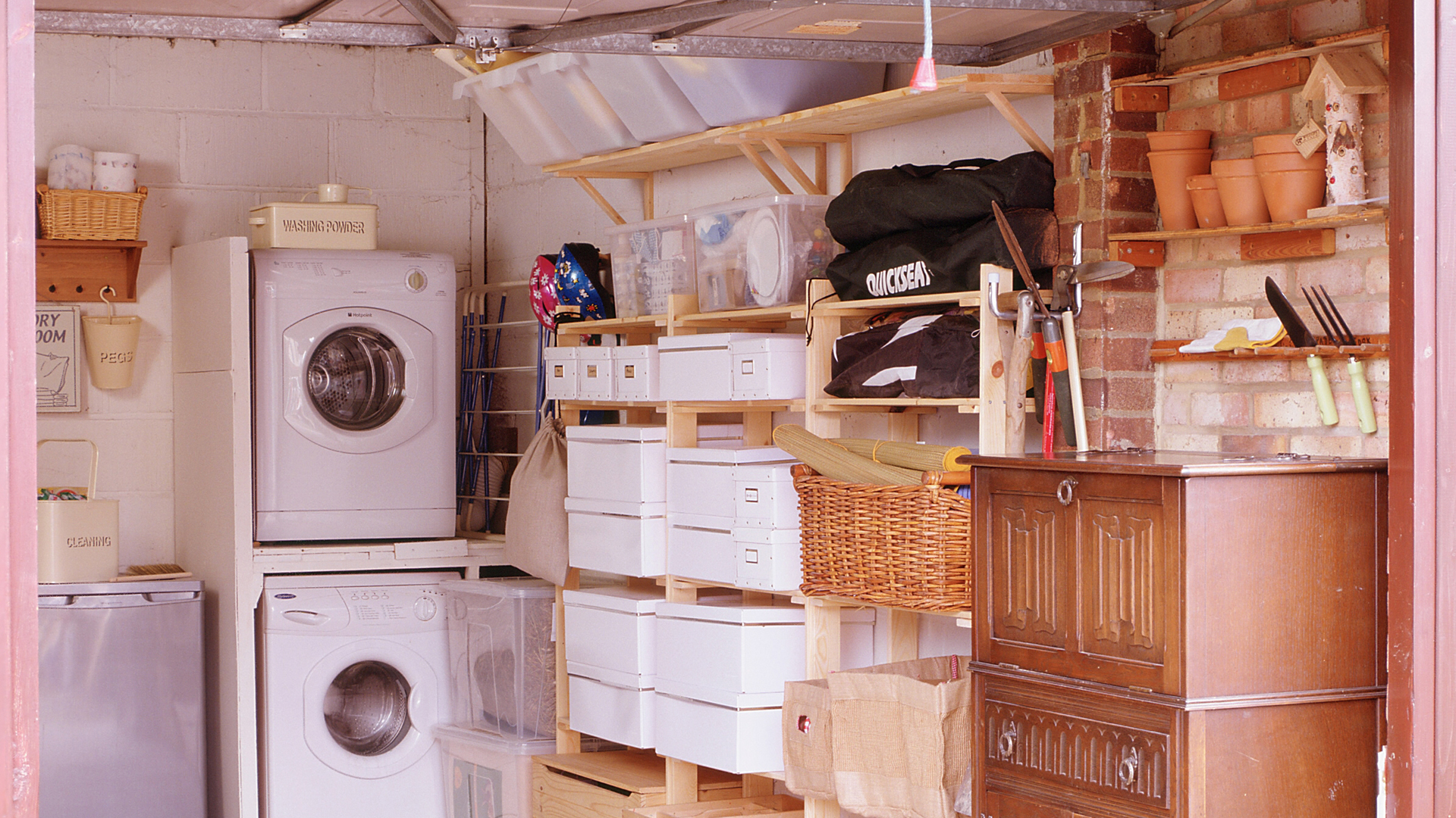 Inside a garage decked out with a wall of storage and stacked washing machine and dryer