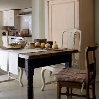 kitchen with freestanding antique furniture, pink dresser and dark farmhouse table and chairs