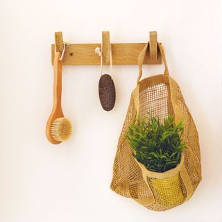 Bathroom brushes and storage basket hung from wooden wall hooks