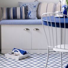 Blue and white breakfast nook with checkered floor tiles and white banquette seating