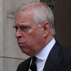 The former Prince Andrew wears a black suit with a white tie and has white gray hair and appears to be pursing his lips