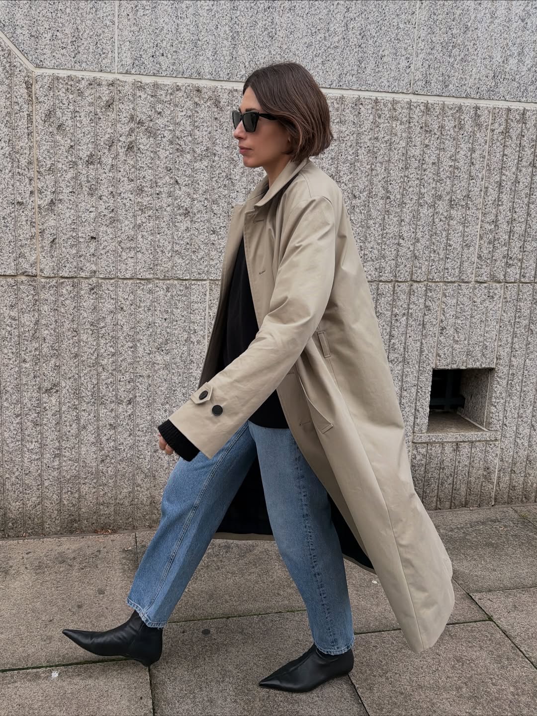 Lucy in flat black boots and a trench