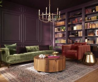 dark purple living room with paneling and painted bookshelves. green velvet couch with a red armchair