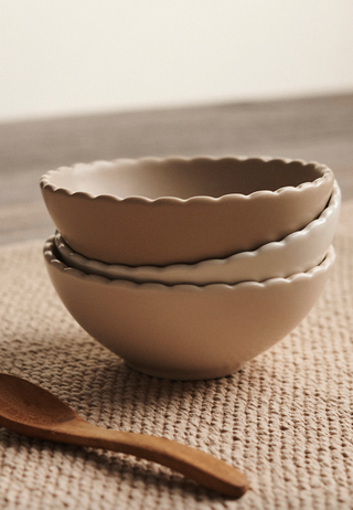 three scallop edge pinch bowls in neutral colors stacked in a pile