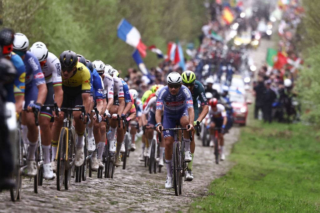 The pack of riders cycles over "La Trouee d'Arenberg" cobblestone sector 19 during the 121st edition of the Paris-Roubaix one-day classic cycling race, 260km between Compiegne and Roubaix, northern France, on April 7, 2024. (Photo by Anne-Christine POUJOULAT / AFP)