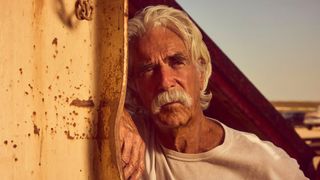 Sam Elliot leans again a bent metal pole