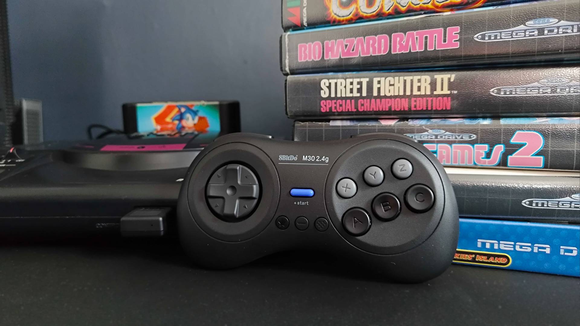 8Bitdo M30 leaning against Sega Mega Drive game boxes next to console.