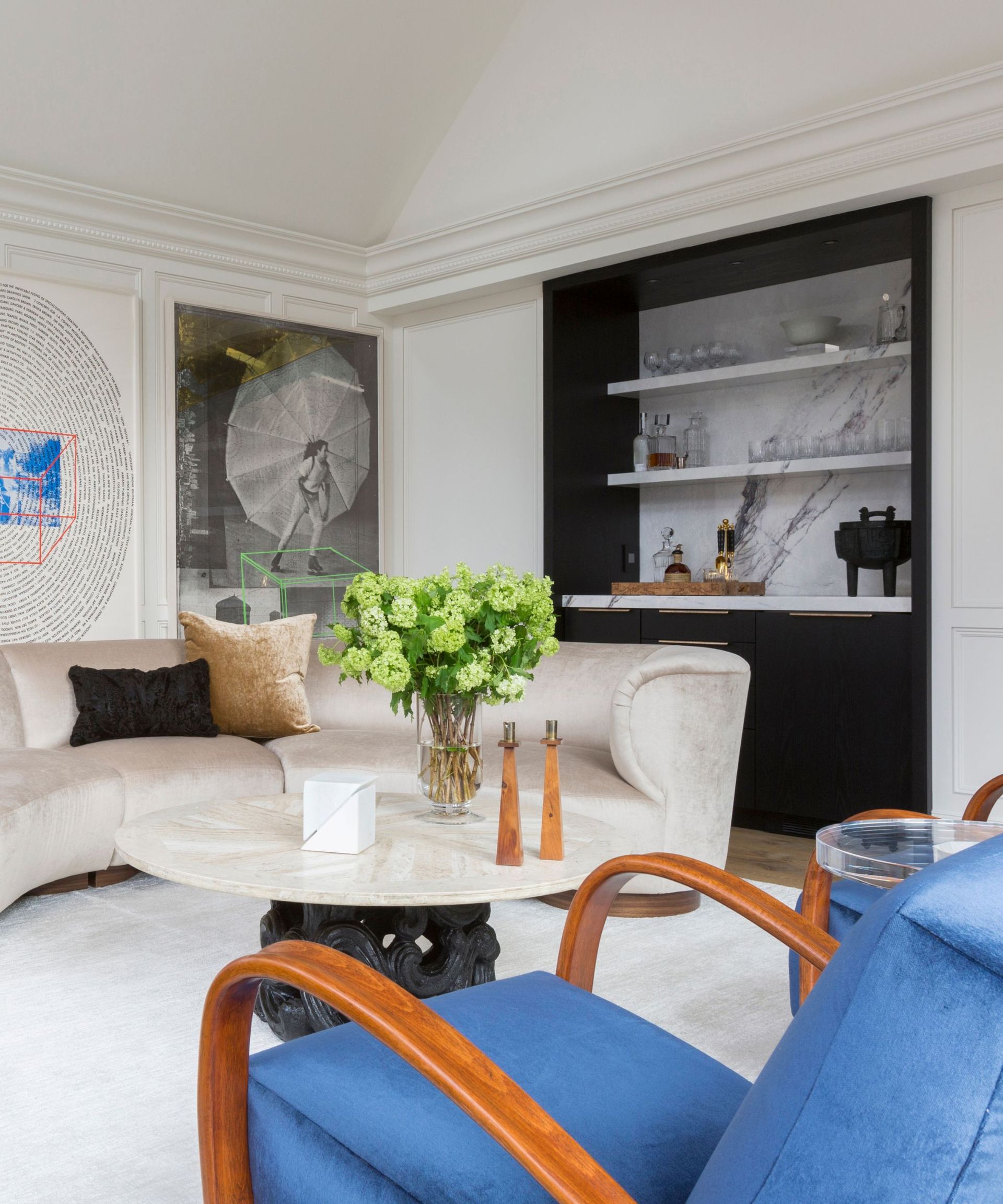 An art deco-inspired living room with a sculptural white couch and blue armchair, as well as a marble mar in the background