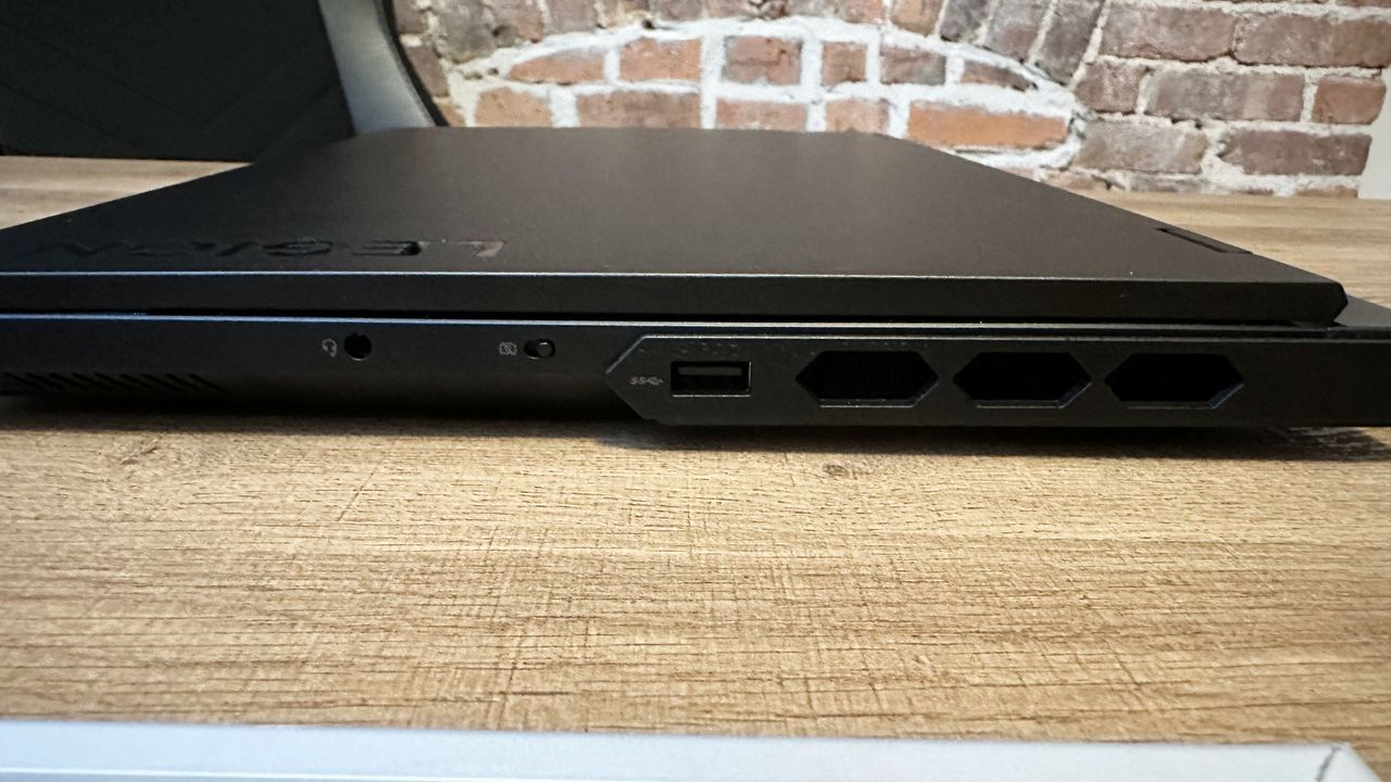 Lenovo Legion Pro 7i (Gen 9) closed on a wood table, highlight ports on the right, including USB Type-A, webcam kill switch, and headphone jack.