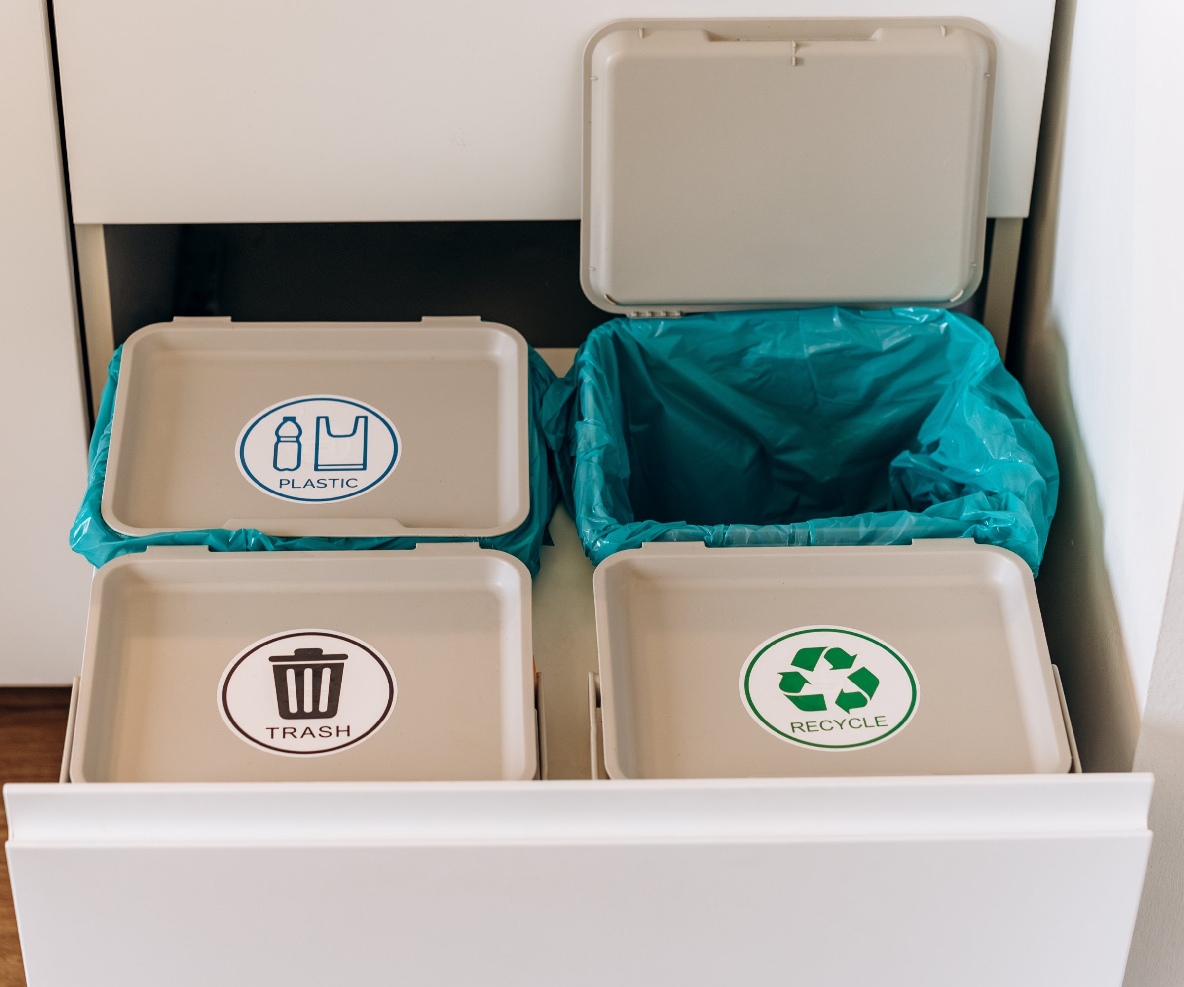 Four labelled bins in a drawer with blue liners inside, and one bin lid open