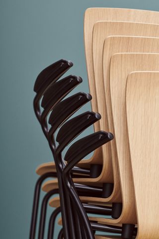 Stack of wooden chairs with black arm rails