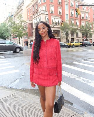 Woman wearing a red tweed suit.