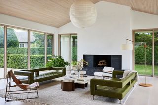 a white living room with a pair of midcentury green sofas