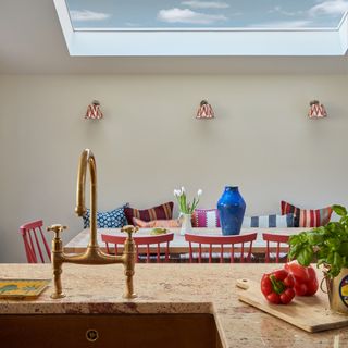 view of the dining table in an open-plan room with colourful chairs and a large skylight overhead