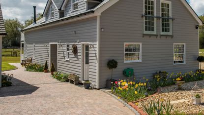 Block paving driveway front garden next to gravel area with spring bulbs including daffodils