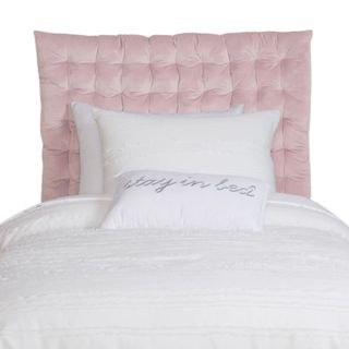 A pink headboard with a white bed