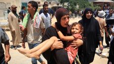 Woman carries girl after Israeli strike in Mawasi, Gaza