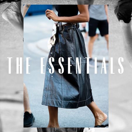 A woman walking down the street in a leather skirt. Overlaid text reads ,"The Essentials"