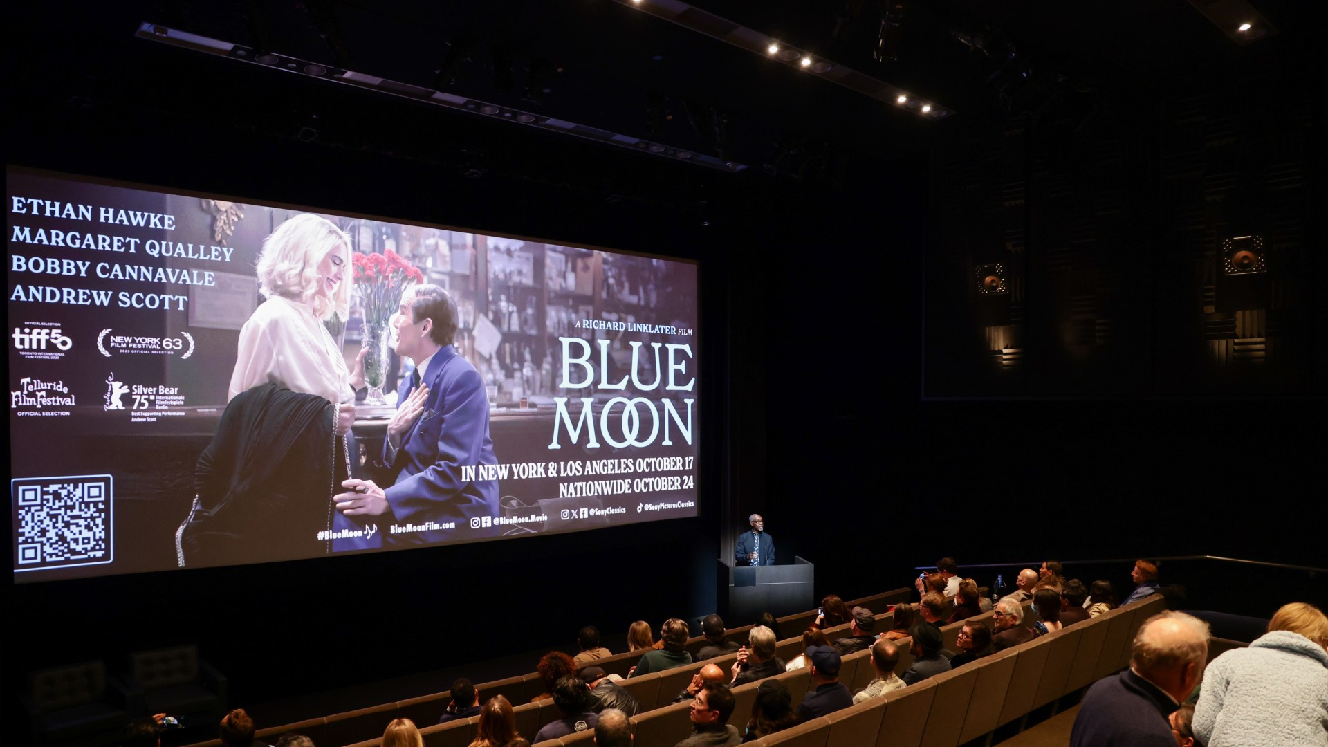 people sit in movie theater seats looking at a screen with the words "blue moon" on it