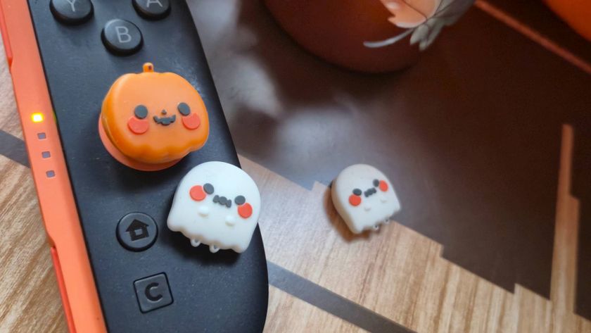 Photo of a pumpkin and ghost-shaped thumb grip sitting on a Switch 2 Joy-Con controller.