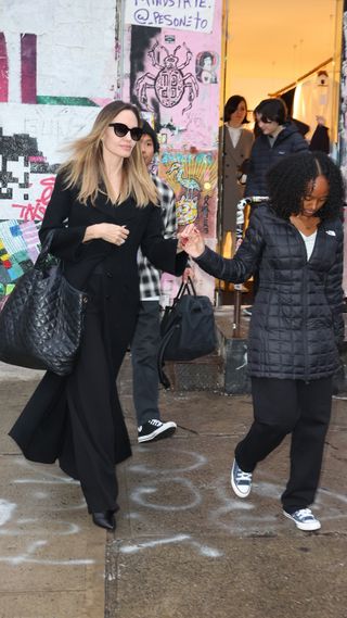 Angelina Jolie wearing an all-black outfit walking with her daughter Zahara.