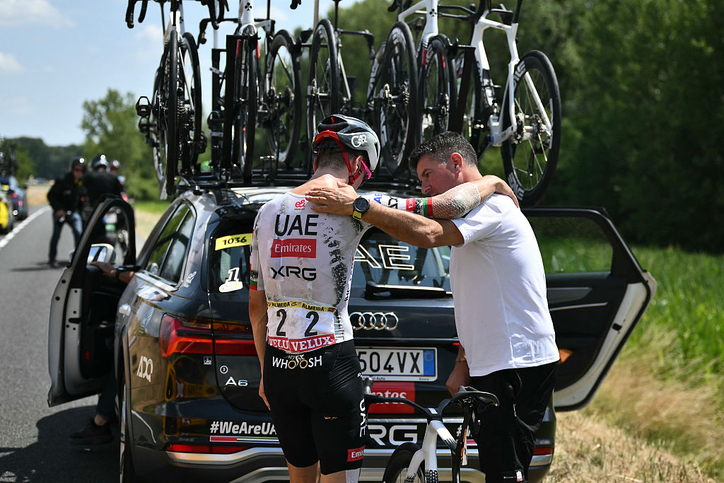 TOPSHOT - UAE Team Emirates - XRG team's Portuguese rider Joao Almeida is comforted by a team staffed member as he prepared to board his team support vehicle after withdrawing from the race on injury, during the 9th stage of the 112th edition of the Tour de France cycling race, 174.1 km between Chinon and Chateauroux, central France, on July 13, 2025. (Photo by Marco BERTORELLO / AFP) (Photo by MARCO BERTORELLO/AFP via Getty Images)