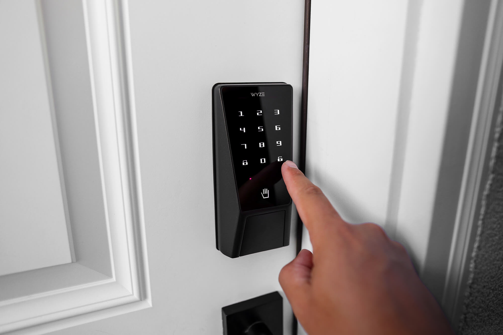 A hand is pressing buttons on the Wyze Palm Lock