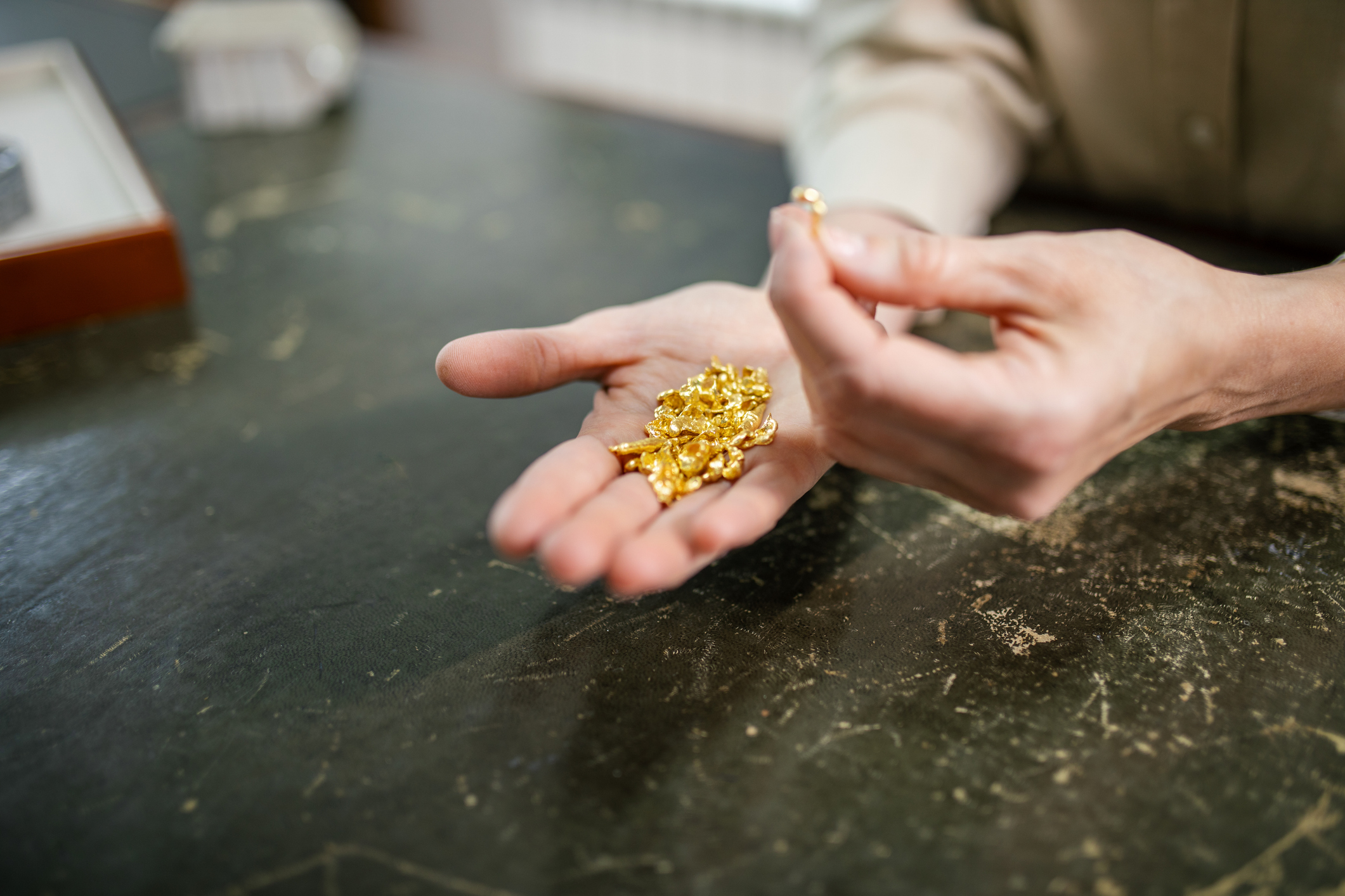 Close-up of hands holding multiple pieces of raw, pure gold