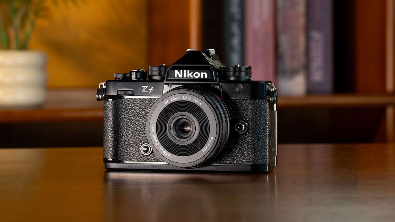 Viltrox AF 26mm F2.8 EVO lens attached to a Nikon camera on mahogany table with bookshelf in background